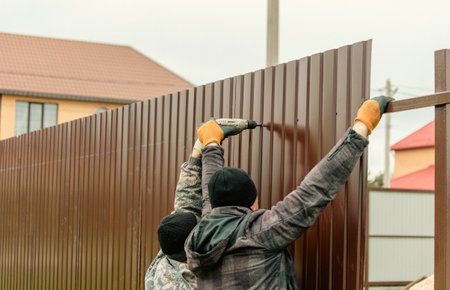 Workers install a metal profile fence.の写真素材