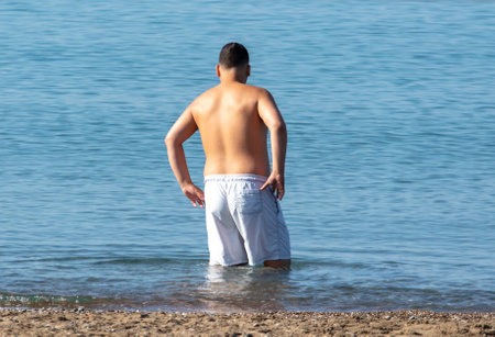 A man in shorts bathes in the blue water of the sea.の写真素材