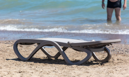 An empty sunbed stands on the beach by the sea.の写真素材