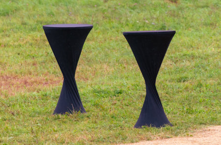 Two black tables on green grass.