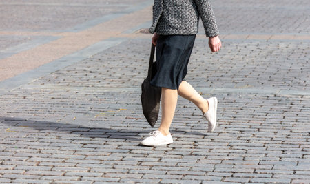 A woman in a black skirt walks along the cobblestones.の写真素材