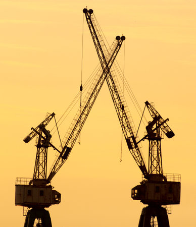 Silhouette of a tower crane against the background of a sunset.の写真素材