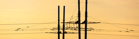 Wires of a trolleybus against the sky at sunset.