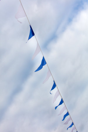 Festive blue white flags against the sky with clouds.の写真素材