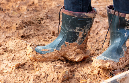 A man in rubber boots walks on clay.