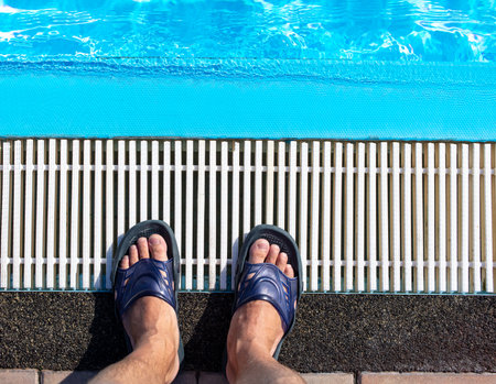 A man's foot in flip-flops on the edges of the pool.の写真素材