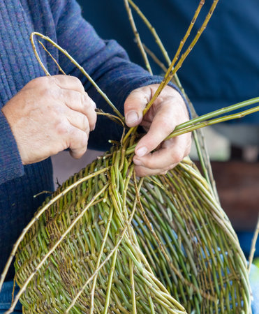 A man weaves a basket with willow branches.