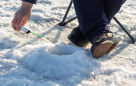 A man catches fish on the ice with a fishing rod.の写真素材