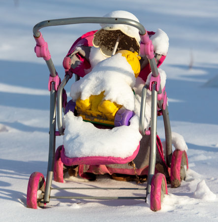 Baby stroller in white snow in winter.の写真素材