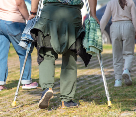 A man with crutches walks in the park. Back view.の写真素材