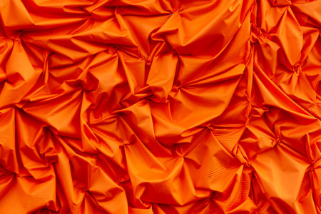 Orange silk crumpled fabric as an abstract background. Texture.