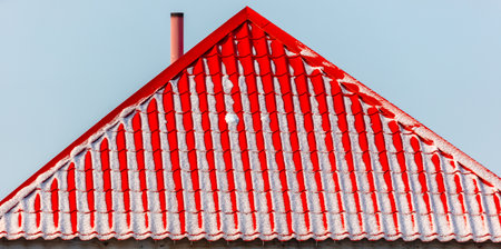 Red roof of a house in the snow in winter.の写真素材