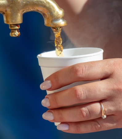 A woman pours tea into a glass from a samovar.の写真素材