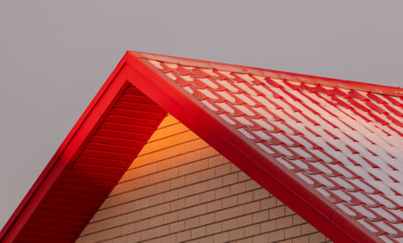 Roof of a house covered in snow at sunset.の写真素材