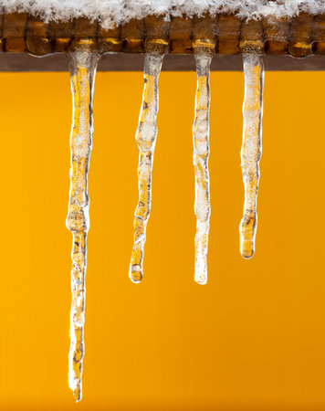 Icicles on a yellow background.の写真素材
