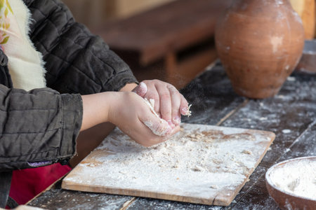 A woman kneads the dough with her hands.