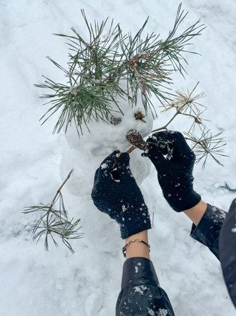 A man makes a snowman outdoors in winter.の写真素材