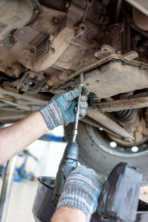 A mechanic at a car service center disassembles a CVT on a car.の写真素材