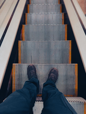 A man's legs on the steps of an escalator.の写真素材