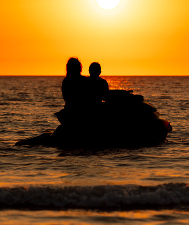 Man woman on a jet scooter on the sea at sunset.
