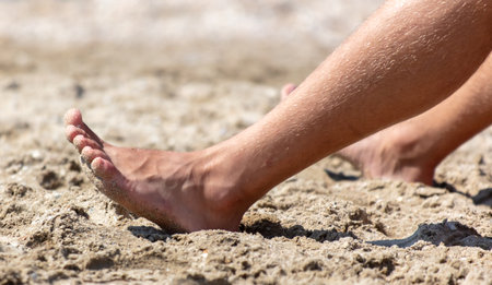 Bare feet of a man on the sand. Close-up.の写真素材