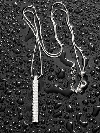 Chain with a pendant in drops of water on a black background.の写真素材