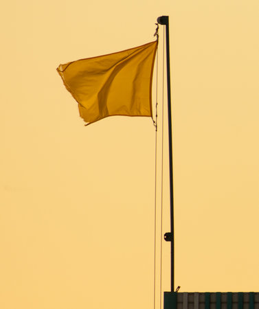 Yellow flag against a blue sky.の写真素材