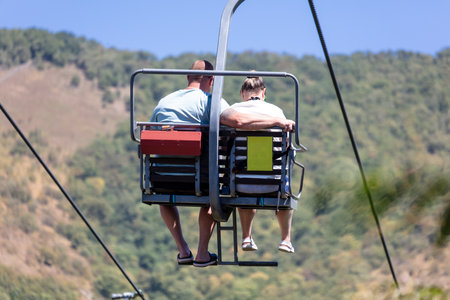 People climb on a ski lift in the mountains against the sky.の写真素材