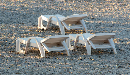 Empty sunbeds on a pebble beach at sunset.の写真素材