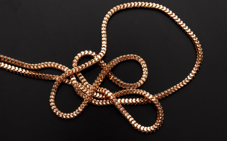 Gold chain isolated on black background. Close-up.