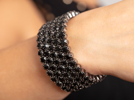 A black bracelet with precious stones is on a girl's hand.の写真素材