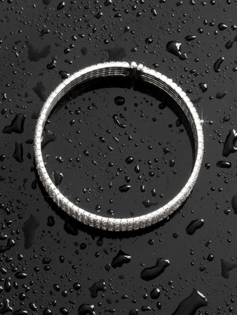 Silver bracelet in drops of water on a black background.の写真素材