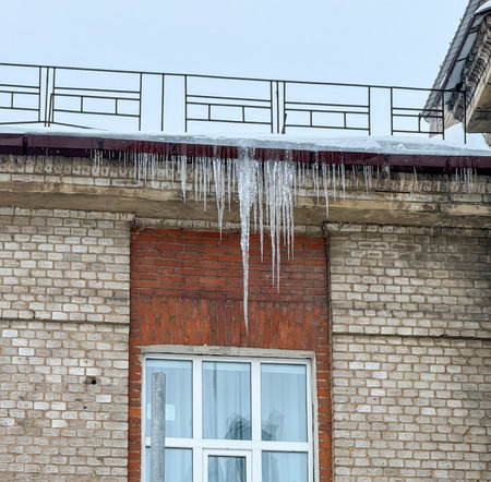 Icicles hang from the brick wall of the building.の写真素材