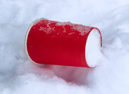 A red paper cup lies on the snow in winter.の写真素材
