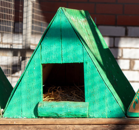 A wood triangle tent with green tints, hay inside, and a rectangular windowの写真素材