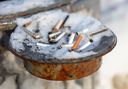 Cigarette butts in the ashtray in the snow.の写真素材