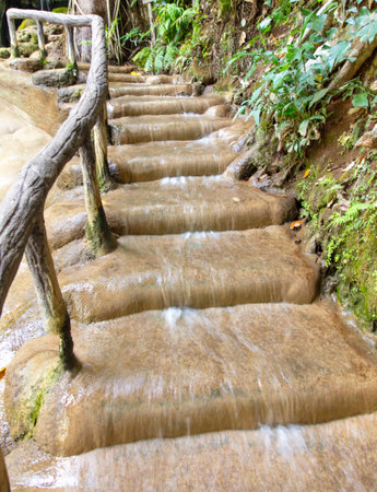 Water flows down a stone staircase in nature.