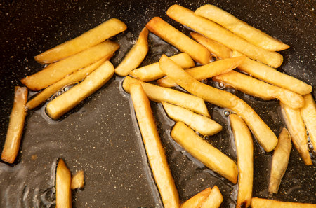French fries are fried in oil in a frying pan.