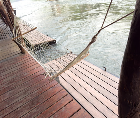 A hammock hangs near a wooden house by the river.の写真素材