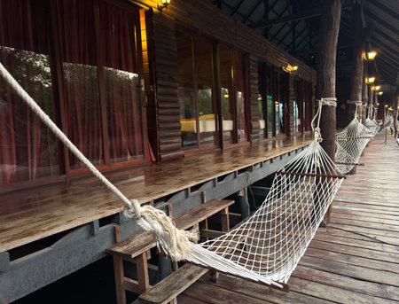 A hammock hangs near a wooden house.の写真素材