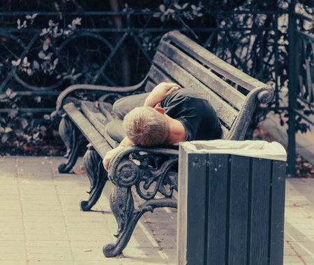 A man sleeps on a park bench.
