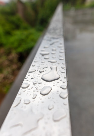 Drops of water from rain on a metal railing.の写真素材