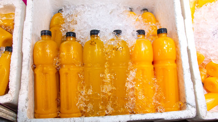 Freshly squeezed juices in plastic bottles in ice at the market.の写真素材