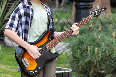 The guy is holding an electric bass guitar in his hands.