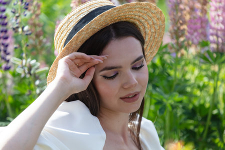Portrait of a brunette girl in a straw hat outdoors in summer.