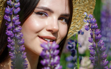 Portrait of a girl in a straw hat with lupine flowers in nature.の写真素材
