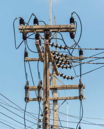Electric wires on a pole against a blue sky.の写真素材