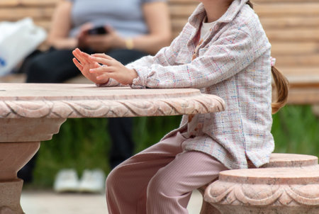 A girl sits at a marble table.の写真素材