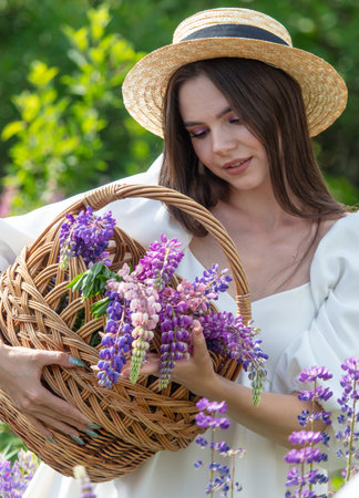 Girl with a hat and a basket in lupine flowers.の写真素材