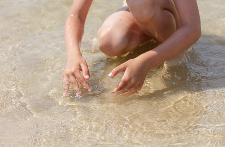 A girl plays in the sand on the seashore.の写真素材